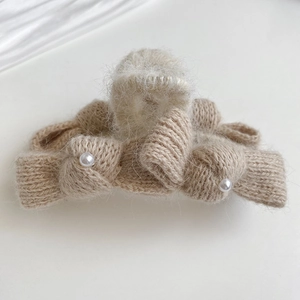 Detail of soft cream knitted hair claw with fuzzy mohair texture and white pearl accents