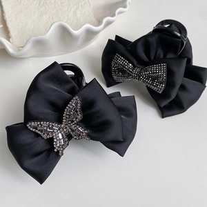 Detailed macro view of black satin bow hair claws with sparkling rhinestone accents