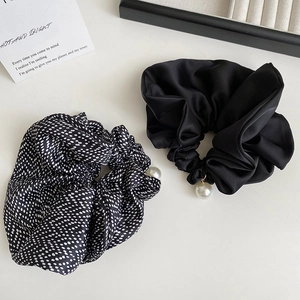 Elegant satin polka dot hair scrunchies set with pearl charms on minimalist background