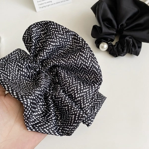 Polka dot satin scrunchie and black pearl hair tie set on a minimalist background