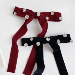 Detail of velvet bow hair clips with sparkling rhinestone flower motifs in black and burgundy