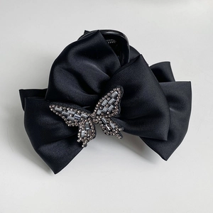 Detailed macro view of black satin bow hair claw clip featuring sparkling rhinestone center