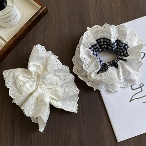 Close-up of double-layer lace scrunchies in white and black plaid on a wooden table