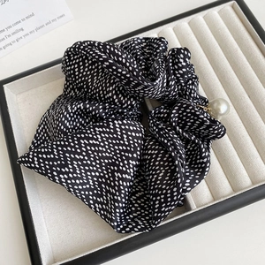 Close-up of black satin polka dot scrunchie with elegant white pearl pendant detail