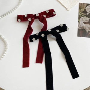 Detailed view of elegant velvet bow hair clips with rhinestone flowers in red and black