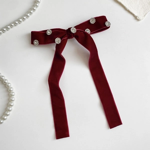 Detail of elegant wine red velvet bow hair clip with sparkling rhinestone flower embellishments
