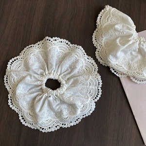 Macro detail of white lace scrunchie with intricate embroidery and ruffled edges