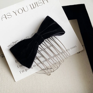 Detailed close-up of a black velvet bow hair comb with seven silver metal teeth on card
