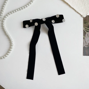 Close-up of black velvet bow hair clip with crystal flowers and long elegant ribbons