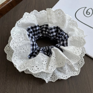 Detailed view of the double-layer lace scrunchie with white floral embroidery and black check