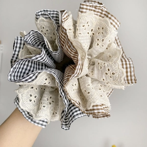 Detailed view of large scrunchie with layered lace embroidery and checkered fabric patterns