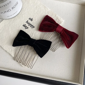 Close-up of velvet bow hair combs in black and wine red with silver metal teeth