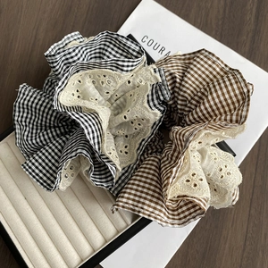 Detailed close-up of retro plaid hair scrunchies with intricate white lace embroidery trim