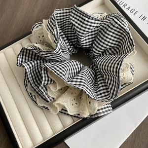 Close-up of black and white gingham scrunchie with delicate white lace edge detail