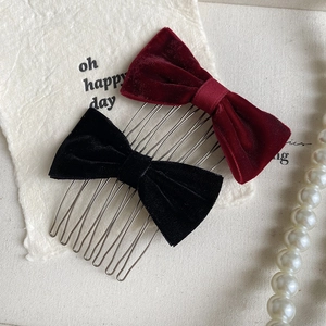 Close-up of velvet bow hair combs in wine red and black on elegant vintage background