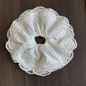 Detail of white lace scrunchie featuring floral embroidery and scalloped hollow edges