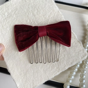 Close-up of a vintage red velvet bow hair comb featuring a sturdy seven-tooth silver metal clip
