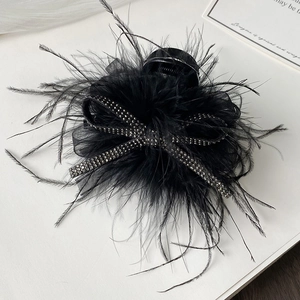 Detailed view of elegant black feather hair claw with sparkling rhinestones and mesh bow