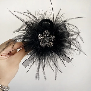 Close-up of black feather hair claw clip with crystal flower detail and net texture