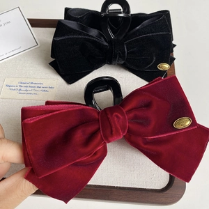 Detail of velvet bow hair claws in black and burgundy with elegant golden metal labels