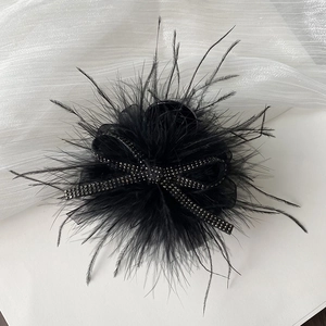 Detail of elegant black feather hair claw with sparkling rhinestone butterfly center