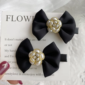 Detail view of black fabric bow hair clips with faux pearl and rhinestone center