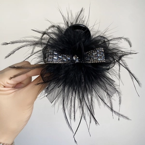 Detail of black feather hair claw clip featuring rhinestone bow and mesh accents