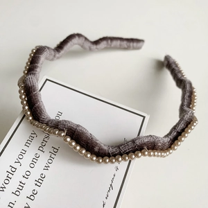 Détail d'un serre-tête ondulé en velours gris avec perles cousues à la main et style rétro