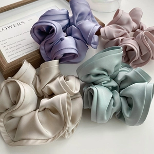 Vue détaillée de quatre chouchous en satin de couleurs champagne, rose, lilas et vert