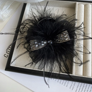 Close-up of black feather hair claw with rhinestone bow in a luxury display box