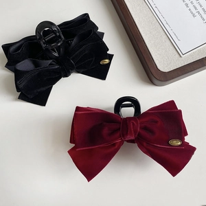 Detailed view of large velvet bow hair claws in black and wine red with gold metal tags
