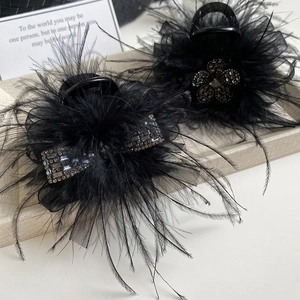 Close-up of black feather hair claw clips with rhinestone bows and floral details