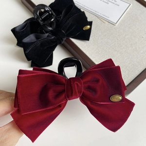 Close-up of velvet bow hair claw clip with gold metal buckle and wings engraving