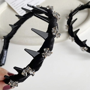 Detail of a black velvet headband featuring punk spikes and crystal accents with a handmade tag