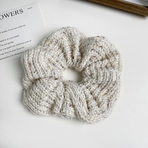 Close-up of knit scrunchie with tweed texture and colorful speckles on white surface