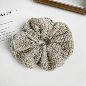Detailed close-up of oatmeal knit scrunchie with thick woolen texture and flecked yarn detail