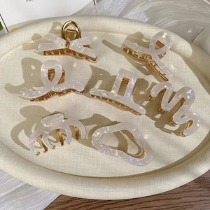 Detailed set of elegant acetate hair claws with pearls and gold metal on a beige tray