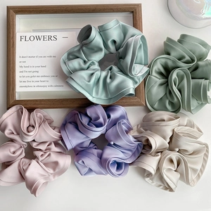 Cinq chouchous en satin assortis aux couleurs pastel sur bureau blanc avec cadre bois