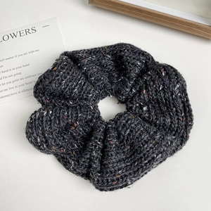 Detailed texture of charcoal grey knitted hair scrunchie with colorful wool speckles