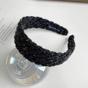 Close-up of a striped knit headband in dark grey with colorful specks and handmade label