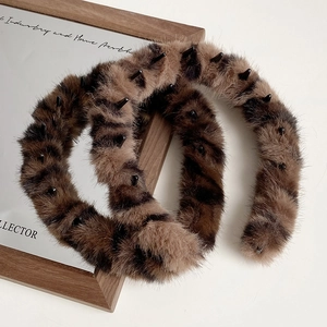 Detail view of leopard print plush headband with non-slip teeth on a wooden board