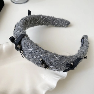 Close-up of grey tweed headband with black satin bow and silver sequin embroidery