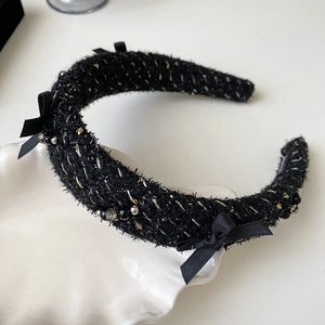 Close-up of black tweed headband with elegant ribbon bow and shimmering bead details