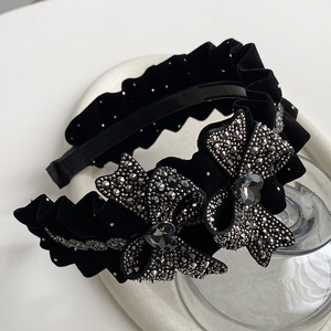 Close-up of velvet pleated headband featuring sparkling rhinestone bows and heart-shaped crystals