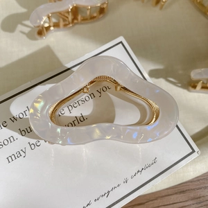 Macro shot of high-end acetate claw clip with iridescent pearl finish and gold frame