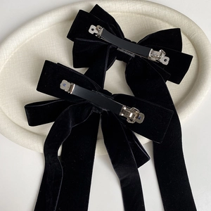 Set of two black velvet bow hair clips with long streamers on elegant ceramic tray