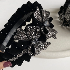 Detailed macro view of black velvet headband featuring rhinestone heart bow accessory