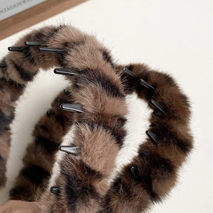 Detailed close-up of leopard print plush headband featuring secure black plastic inner teeth