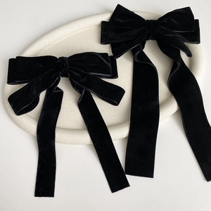 Detail of elegant black velvet hair bows with long ribbons on a beige tray