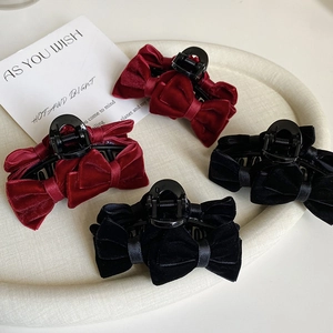 Detailed close-up of premium velvet bow hair claws in burgundy and black on a white tray